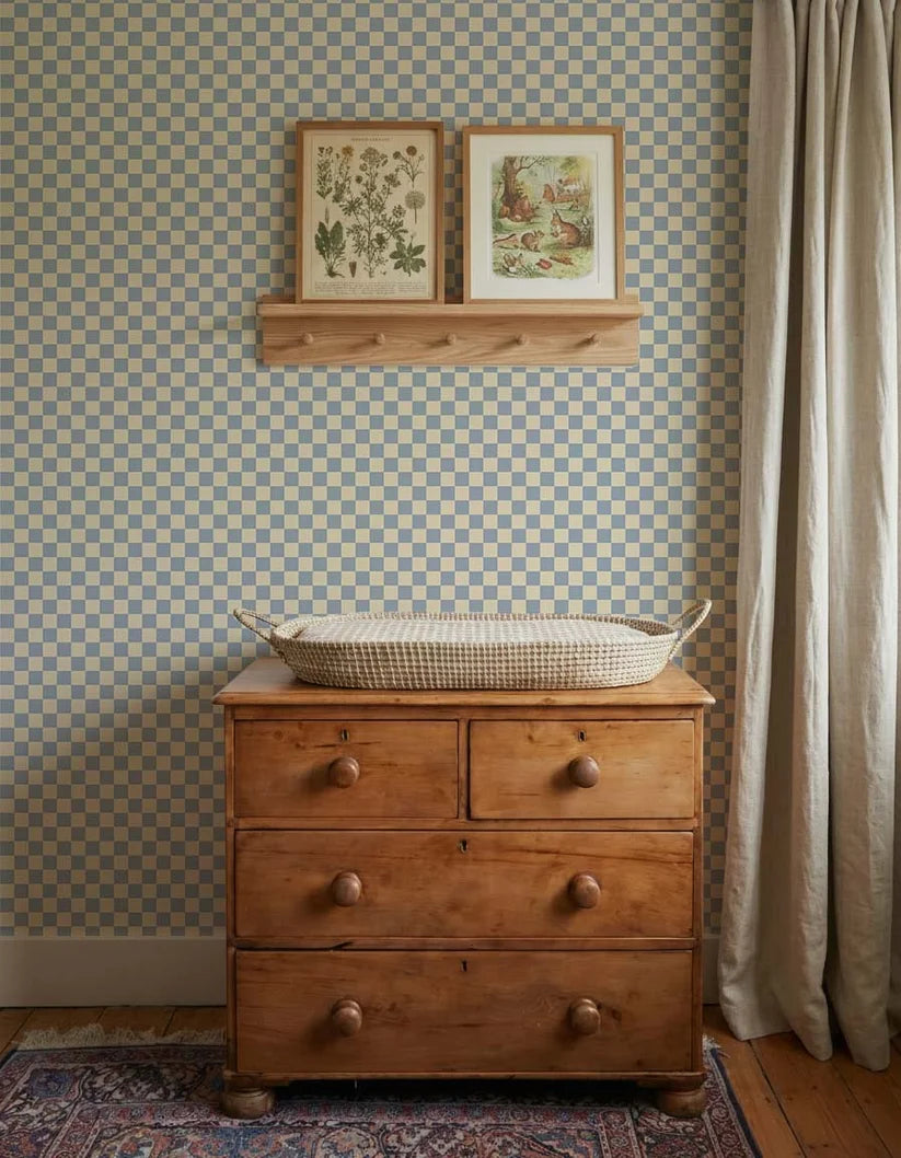 Dambord Lichtblauw – Atelier Chien: behang achter een houten commode met verschoonmand.